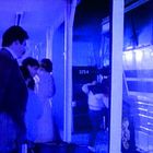 Text: "3254". Menschen steigen in einen Bus ein. Die Szene ist in blaues Licht getaucht.