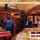 „Der neue Bud Spencer Film“. Titel: „Bud Spencer Der Bomber“. Regie: Michele Lupo. Ein lebhaftes Restaurant mit Leuten.