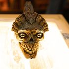 Text: "Visual Productions 320". Eine kunstvoll verzierte, metallische Totenkopf-Skulptur mit markantem Gesichtsausdruck.