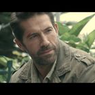 Ich kann den Text nicht lesen. Ein Mann in einer olivgrünen Jacke schaut nachdenklich in die Ferne. Hintergrund: Grünpflanzen.