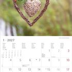 Kalender für Januar 2027. Dekoration: Herz aus Zweigen, darin ein Herz aus Samen, an Zweig hängend. Hintergrund unscharf.