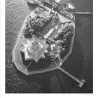 02 unten links, 1 bis 28 oben. Luftbild einer Insel mit einer großen Statue und Anlegestellen.