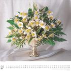 01, Januar, Montag, Dienstag. Ein kunstvoller Blumenstrauß mit weißen und gelben Blüten in einer silbernen Vase.