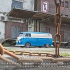 Text: "JANUAR 2027" und Kalenderdaten. Ein blauer VW-Bus steht vor einer alten Fabrik, davor eine rostige Kette.