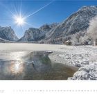 "1. 2027" und Kalendertage darunter. Schneebedeckte Berglandschaft und gefrorener See bei sonnigem Wetter.