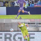 Text: "Vorjahresabbildung"
Zwei Fußballtorhüter in Aktion. Einer in lila, der andere in grün. Im Hintergrund Fans und Tribünen.