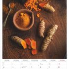 Kalenderblatt Januar 2027. Foto mit ganzen und geschnittenen Kurkuma-Wurzeln und Pulver auf Holzuntergrund.