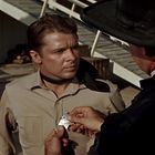 Jemand steckt einem Mann ein Sheriff-Abzeichen mit "Marshal" an, beide tragen Westernkleidung.