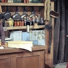 Zwei elegant gekleidete Frauen in einem rustikalen Geschäft mit Regalen voller Keramiken und Vorratsgläsern.