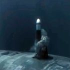 Ein U-Boot unter Wasser feuert eine Rakete ab, die durch eine Wolke aus Blasen und Wasser aufsteigt.