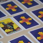 "Ritter der Münzen" steht auf einer Tarotkarte. Mehrere Karten sind mit Kreuzen und Rosen in Gelb und Rot auf blauem Hintergrund.