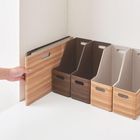 Keine erkennbaren Texte. Eine Hand ordnet Ordnerhalter in Holzoptik in einem Regal an.