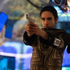 Keine relevanten Texte vorhanden. Eine Person in Schutzkleidung zielt mit einer Pistole in einem Raum mit Bildschirmen.