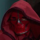 Ein rotes Gewand und eine rote Maske mit schwarzen Details, die an ein Gesicht erinnert.