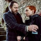 Ein Mann gibt einer Frau einen Beutel mit blauen Pillen, sie stehen in einer steinigen Umgebung.