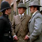 Ein "NOTICE" mit "CHILD FOUND" hängt. Drei Männer in historischer Kleidung stehen in einer Backsteingasse zusammen.