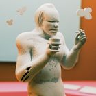 Keine erkennbaren Texte. Illustration einer Figur mit Tasse und Zigarette, umgeben von fliegenden Objekten.