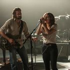 Ich kann die Personen nicht identifizieren. Zwei Musiker auf Bühne: Mann mit Gitarre, Frau singt in Mikrofon in schummrigem Licht.