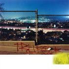 Rotes Graffiti mit dem Schriftzug "TRUFFAUT" auf einer Mauer, im Hintergrund ein beleuchtetes Stadtpanorama.