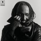 "Brainfeeder Records Stereo" oben links. Ein lächelnder Mensch mit Dreadlocks und Lederjacke in Schwarz-Weiß.