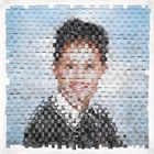 Ein Schuljunge lächelt. Das Bild wirkt wie ein Mosaik aus kleinen, verflochtenen Quadraten.