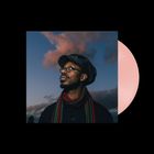 Ein Mann mit Brille und Mütze schaut nach oben, umgeben von einem blauen Himmel mit rosa Wolken. Links steht er im Mittelpunkt.