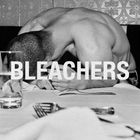 Text "Bleachers" über einem Mann, der mit dem Kopf auf einem Tisch ruht, umgeben von Geschirr in einem Restaurant.