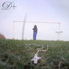 „Sassy 009 DREAMER“. Eine Person steht am leeren Fußballtor, Vordergrund mit unscharfem Kreuz im Gras.