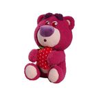 Ein lila Teddy hält eine rote Erdbeere mit weißen Punkten. Er hat ein großes, freundliches Gesicht.