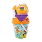 Ein Set von bunten Sandspielzeugen in einem Netz verpackt, mit einem Dino-Motiv auf dem blauen Eimer.