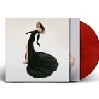 Eine Frau in einem langen schwarzen Kleid, das sich dramatisch auf dem Boden ausbreitet. Ein rotes Vinyl ist sichtbar.