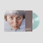 Ein blaues Vinyl neben einem Porträt eines jungen Menschen mit einem leicht neutralen Gesichtsausdruck.