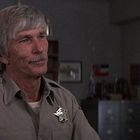 Ein Mann in Sheriff-Uniform mit Abzeichen unterhält sich in einem Büro mit Gittern und Schränken. USA-Flagge auf dem Ärmel.