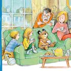Text links: "At Home" und Suchliste mit: Teekanne, Uhr, Teelöffel, Fußball, Kuchen, blaue Schuhe, Stricknadeln, fünf Tassen.  
Illustration: Menschen und ein Bär sitzen gemütlich auf einem grünen Sofa, trinken Tee, im Hintergrund ein Fenster.
