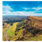 Seite 16: Arthur's Seat Edinburgh. Beeindruckende Aussicht mit grünem Hügel und Stadtansicht im Hintergrund unter blauem Himmel.
