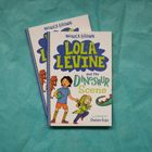 Text: "Monica Brown, Lola Levine and the Dinosaur Scene, Illustrated by Chelen Ecija." Cartoonstil mit zwei Kindern, Dino-Requisiten.