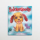 "Snickerdoodle", "Victoria Kann". Niedlicher Welpe mit rotem Fell, sitzt neben violettem Kätzchen und Wollknäuel.