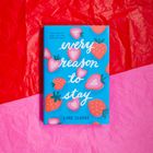 Buchcover mit "Every reason to stay" von Lane Clarke, Erdbeer- und Herzmuster auf blauem Hintergrund, Hintergrund aus rotem und pinkem Papier.
