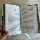 Seiten 26-27 eines Buches mit englischem Text über Mosaku und Minokichi. Ein blaues Leseband hängt lose herunter.