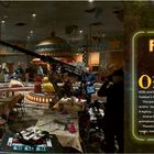 "Part Four: Five Nights at Freddy's 2. Of course, one movie wasn’t nearly enough... the filmmakers were still doing their movie magic, too!"  
Eine Filmkulisse mit Crewmitgliedern, Kameras und Set-Elementen in einem Pizzeria-Setting.