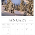 Texte: "January", Feiertage, Monatsübersicht. Schneebedeckte Bäume vor Berglandschaft unter hellem Himmel.