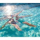 Zitat: "There's something for everybody... There's a lot to do." Fünf Personen treiben synchron im Wasser eines Pools.