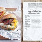 „Steak & fried egg baps with mustard butter“ ist zentriert. Zwei Brötchen mit Steak, Ei und Kräutern liegen auf Papier. Rechts sind Zutaten und Zubereitung beschrieben. Ein illustriertes Huhn befindet sich unten rechts.