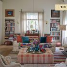 "The Living Room." Farbenfrohes Wohnzimmer mit Büchern, einem weißen Kamin, bunter Deko und gemütlichen Möbeln.