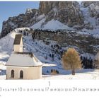 "Grödner Joch" und "CASARES EDITION". Eine schneebedeckte Kapelle vor beeindruckenden Bergketten.