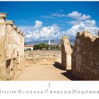 Ausgrabungen in Paphos, Ruinen mit Säulen vor blauem Himmel, im Hintergrund ein Leuchtturm.