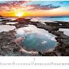 Text: "Maori Bay Sunset"; Zahlen 1-31.  
Foto von einem Sonnenuntergang am Meer, Felsen und Pfützen.