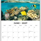 Juni 2027 Kalender mit Unterwasser-Korallenriff und tropischer Insel im Hintergrund, Himmel mit Wolken.