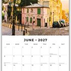 Kalenderseite für Juni 2027, darunter eine Straßenszene mit bewachsenem Gebäude und Frau.
