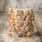 Ein rustikaler Holztisch mit gestapelten Brotscheiben, die mit Haferflocken bestreut sind.